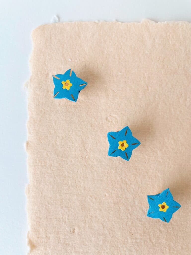 Pin’s myosotis en cuir surcyclé, finition dorée, bijou artisanal délicat.