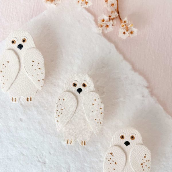Broche en cuir représentant un harfang des neiges, bijou artisanal avec dorure.