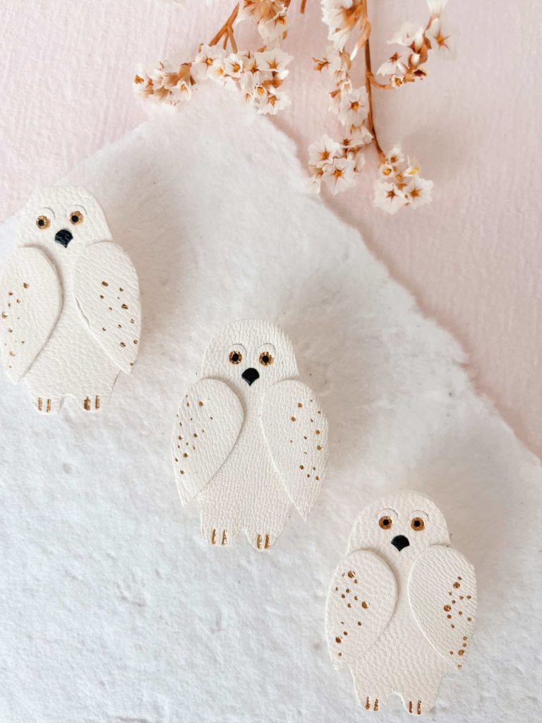Broche en cuir représentant un harfang des neiges, bijou artisanal avec dorure.