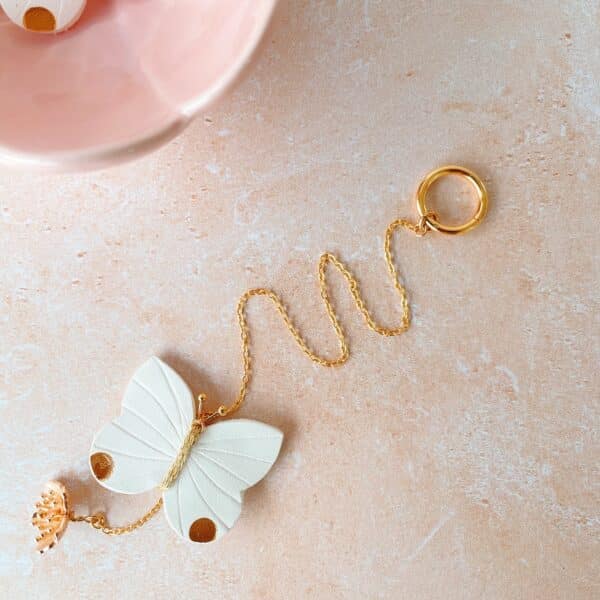 Suspension poétique papillon en cuir fait main, bijou d’intérieur avec fleur de cerisier et quartz rose, à suspendre sous une étagère ou un luminaire.