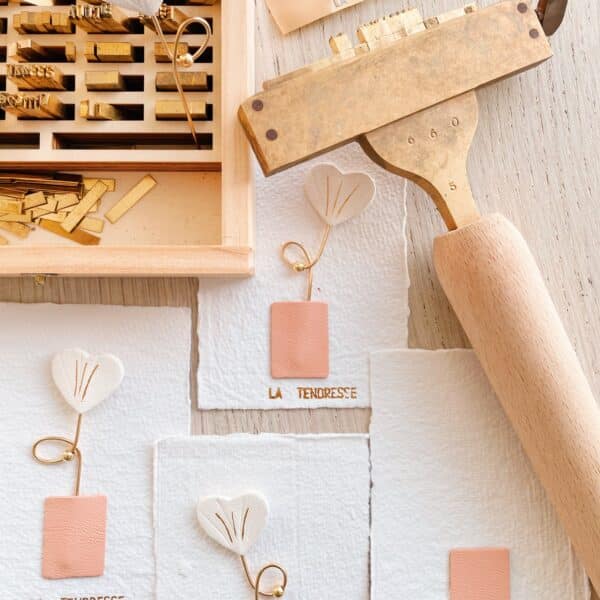 Grigris Fleur d’Amour en cuir ivoire sur cartes artisanales dorées “la tendresse”