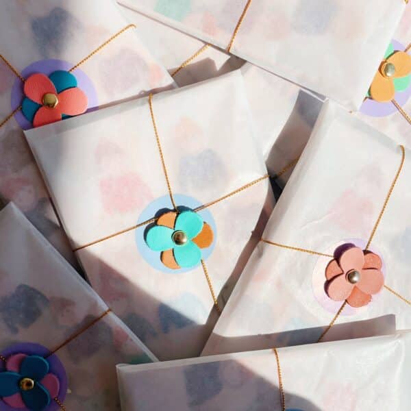 Pochette surprise artisanale contenant une broche fleurie, un pin’s et des trésors poétiques Titre