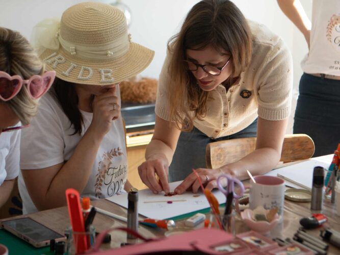 Camille accompagne des participantes lors d’un atelier créatif autour du cuir.